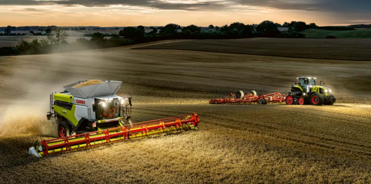 Modern agricultural equipment harvesting at sunset